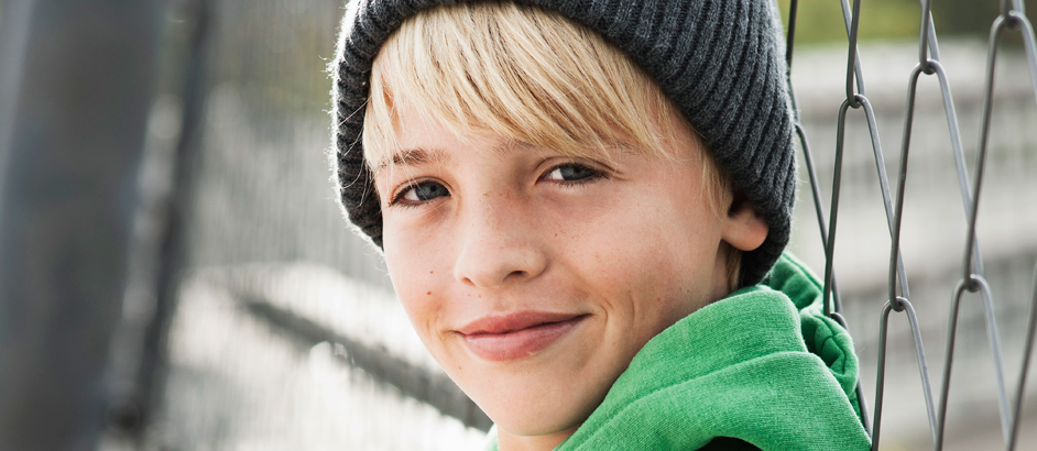 Blonder Junge mit Mütze blickt in die Kamera