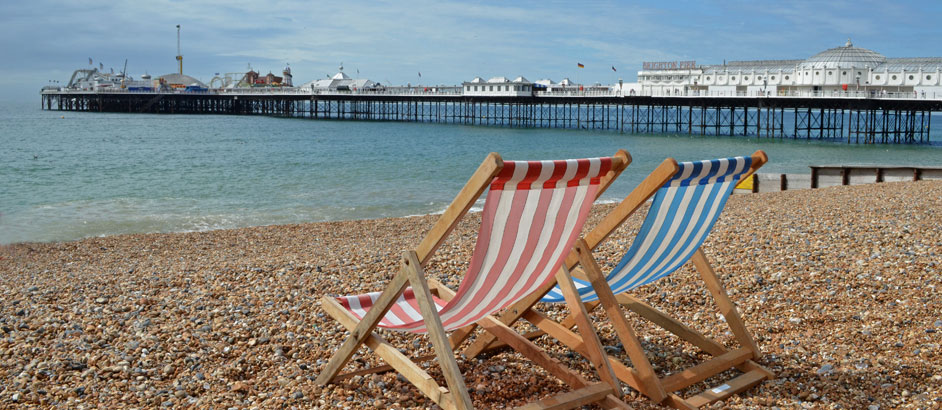 Blick auf die Seebrücke in Brighton, im Vordergrund stehen  zwei Liegestühle.