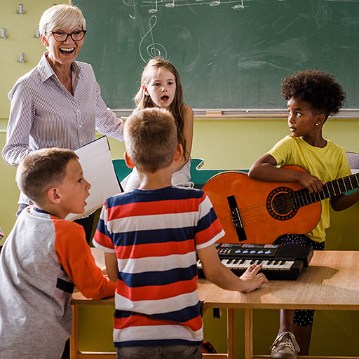 Eine Lehrerin singt gemeinsam mit Grundschülern in einem Klassenzimmer.