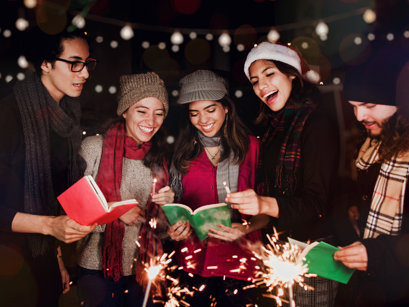 Eine Gruppe junger Menschen in Winterkleidung singt gemeinsam im Dunkeln mit Kerzen in der Hand.