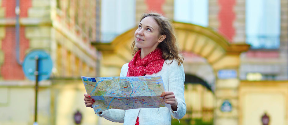 Eine Frau steht vor einem Tor und hält einen Stadtplan in den Händen