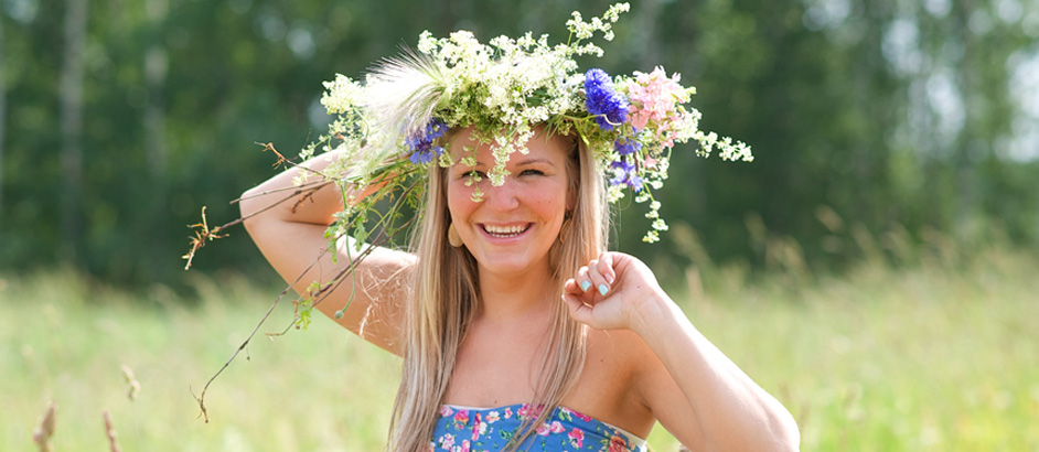 Frau mit Blumenkranz auf dem Kopf lacht in Kamera