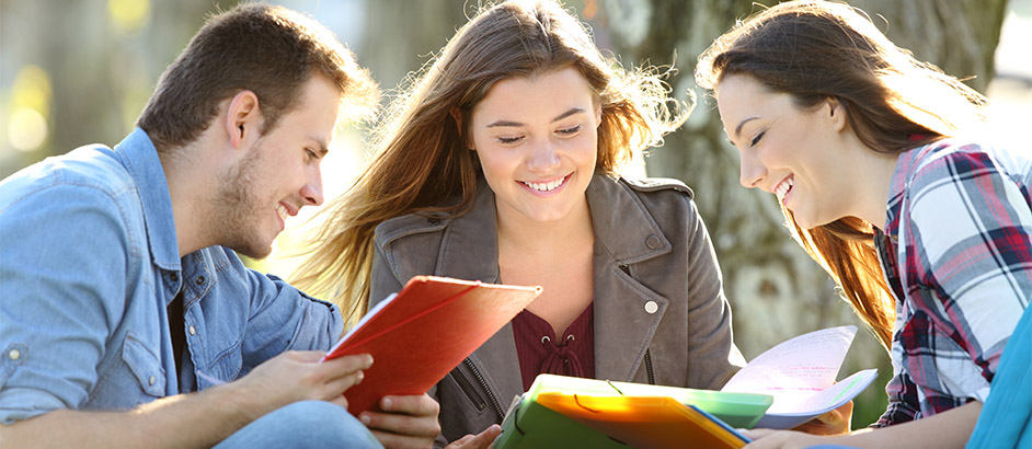 Ein junger Mann und zwei junge Frauen lesen in ihren Unterlagen
