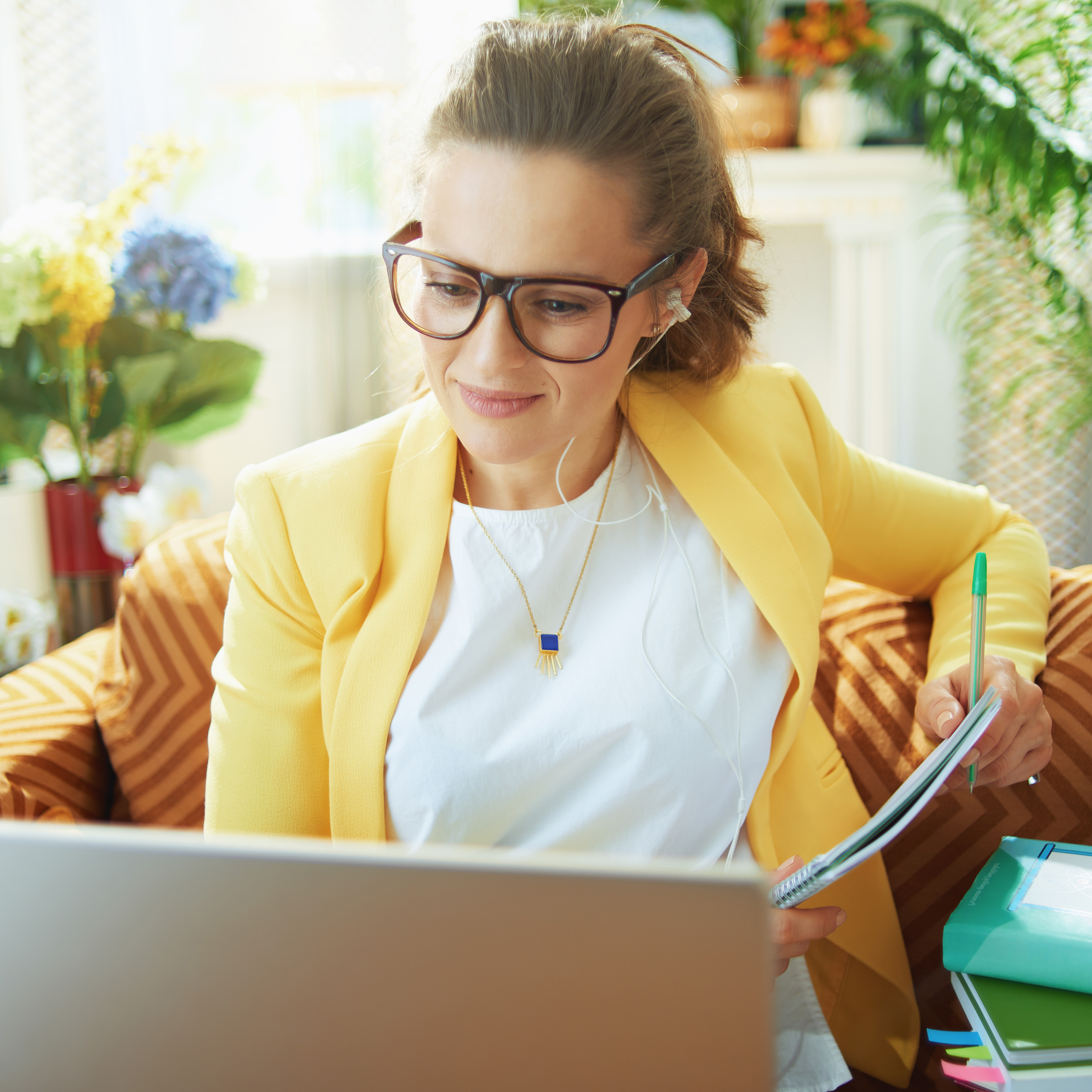 Junge Frau sitzt zuhause auf der Couch vor einem Laptop und lernt.
